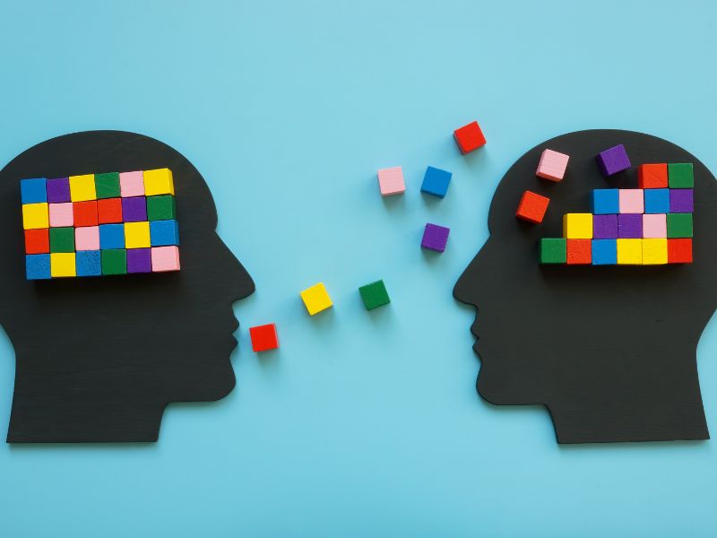 Symbolbild für Gesprächstherapie: Zwei Köpfe, von denen einer bunte Klötzchen als Gedanken an den anderen überträgt, um Ordnung zu schaffen. Veranschaulichung der Arbeit eines Heilpraktikers für Psychotherapie in Rudolstadt.