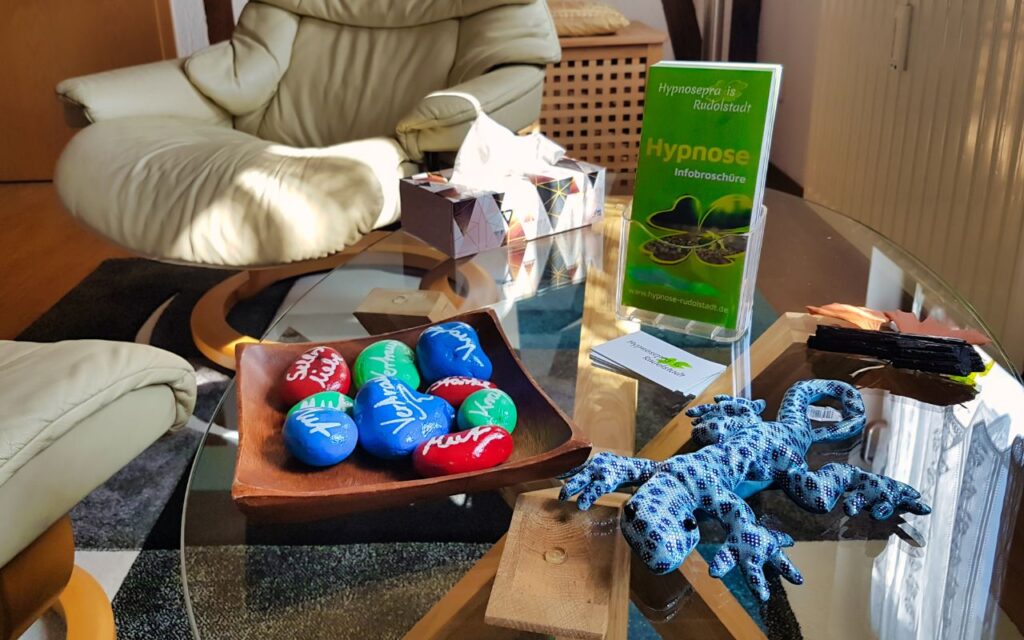 Blick in den gemütlichen Raum der Hypnosepraxis Rudolstadt mit dem bequemen Hypnosesessel und positiven Symbolsteinen auf dem Tisch.